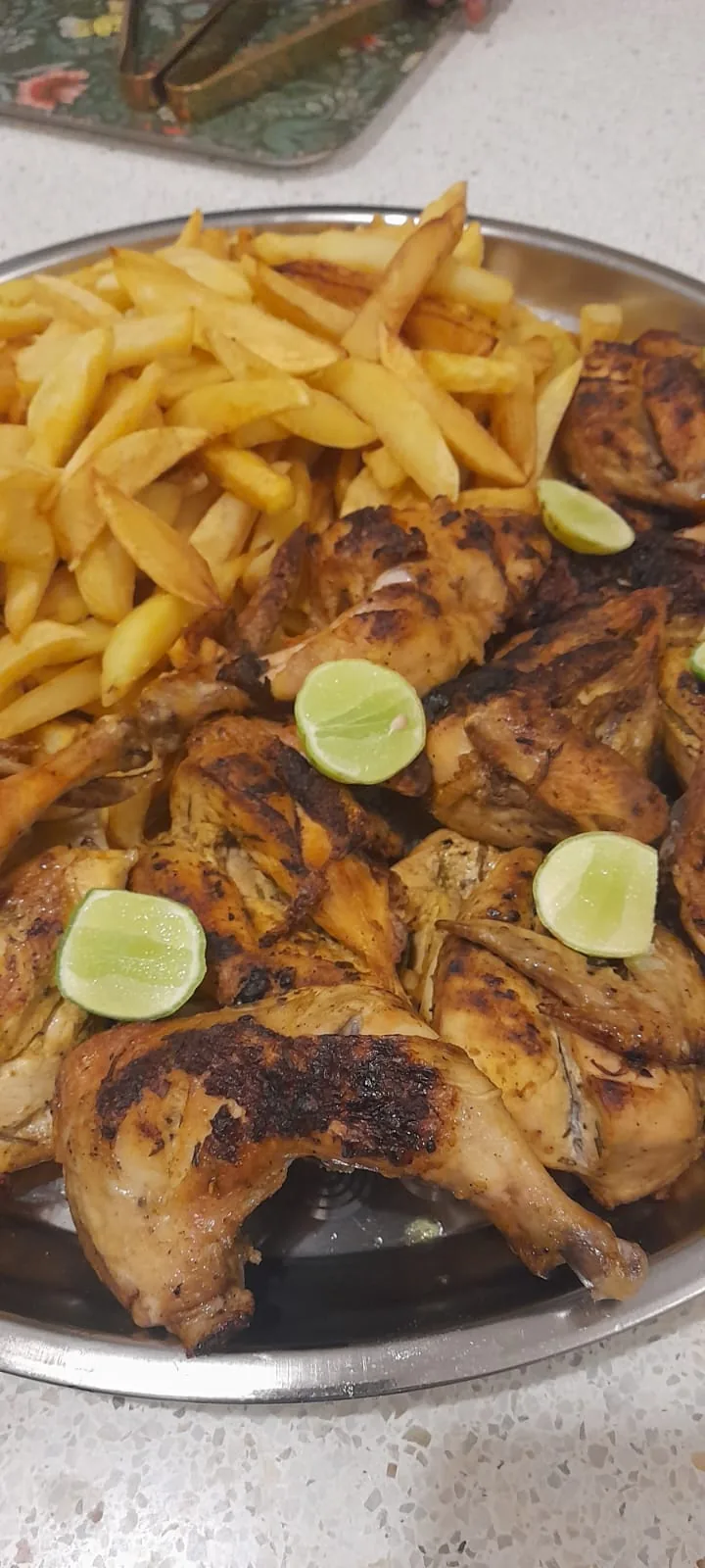 A tray of grilled chicken, chips and lime wedges
