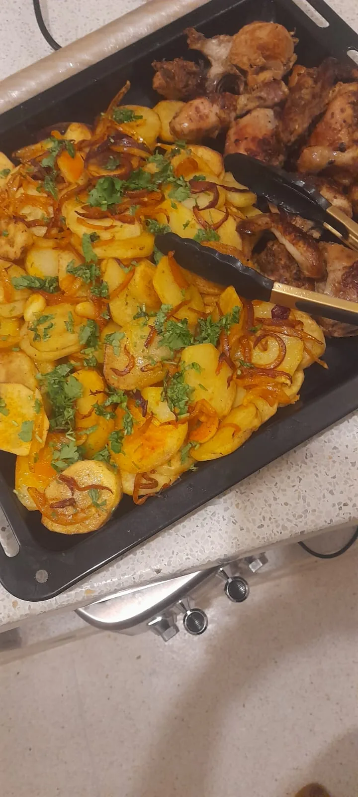 Golden sliced potatoes with herbs beside pieces of grilled meat