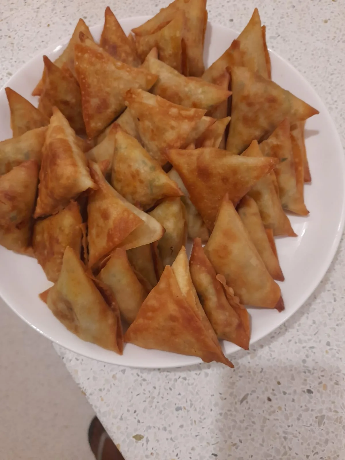 A plate piled with crisp triangular samosas