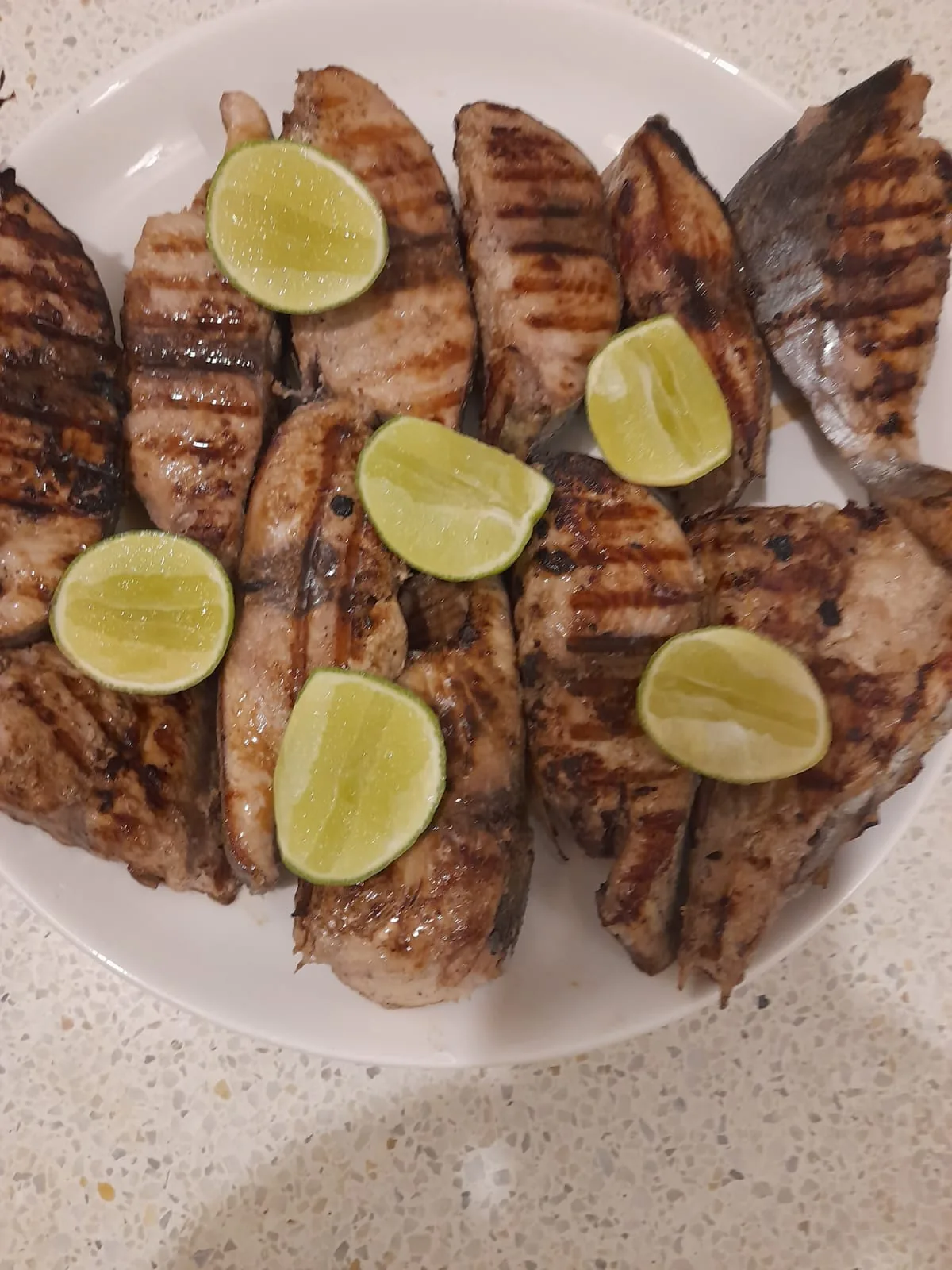 Grilled fish fillets with dark grill marks and lime wedges