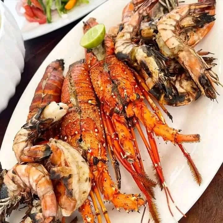 Split lobster and large prawns on a seafood platter with lime