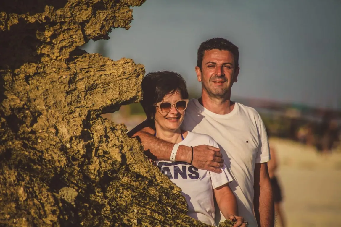Giovanna and Germano smiling together beside a coastal rock formation