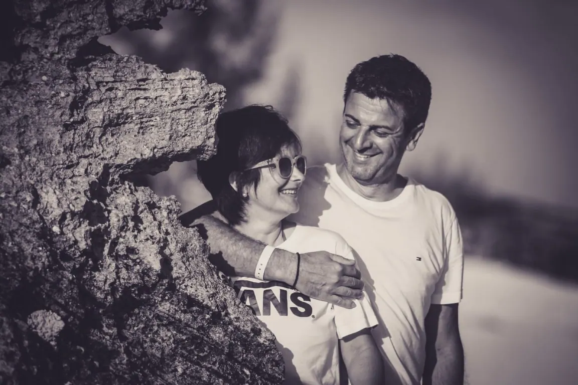 Black-and-white portrait of Giovanna and Germano smiling at each other by the coast