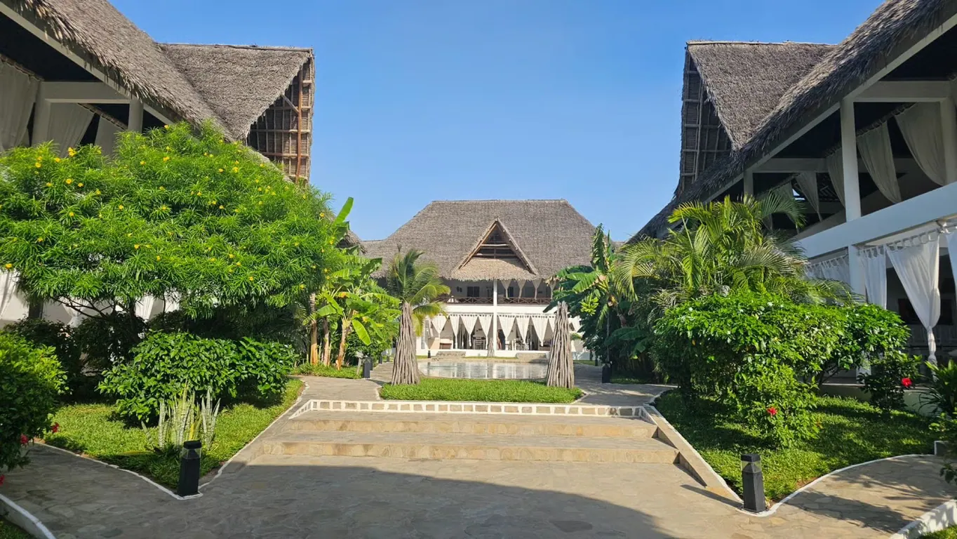 Tropical courtyard and paths between white thatched buildings under a blue sky