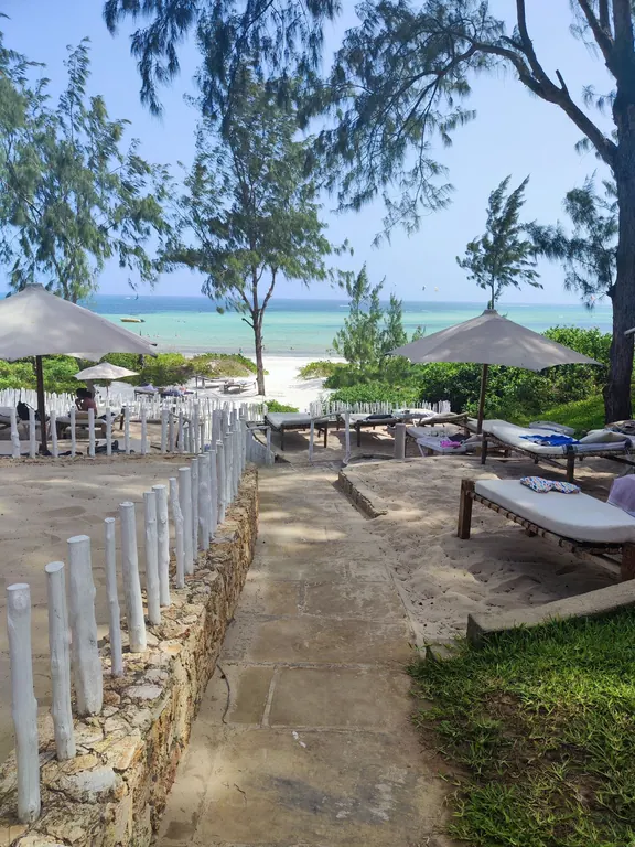 Stone path through shaded loungers and umbrellas toward the turquoise ocean