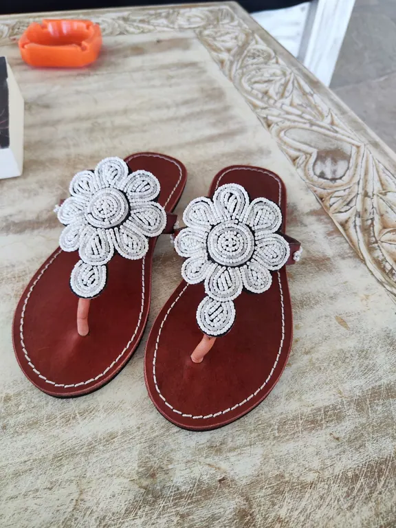 Brown leather sandals with large white-and-silver beaded flower decorations